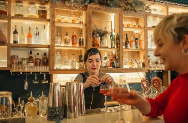 En kvinnelig bartender lager en drink til en gjest på baren