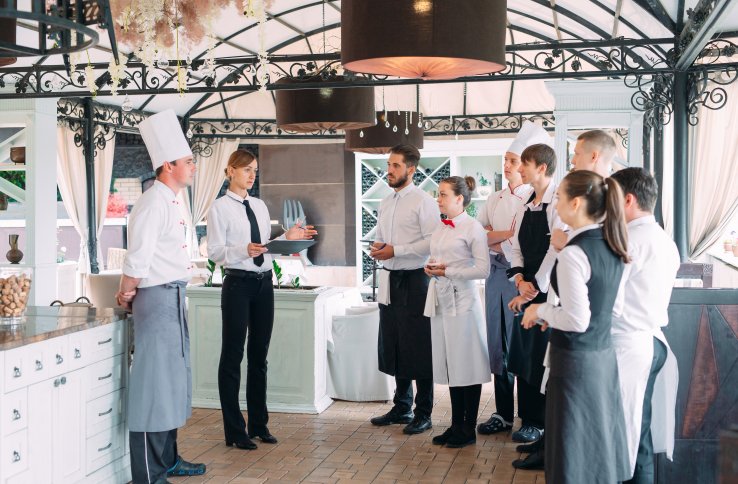 En hovmester planlegger serveringen med servitører og kokker 