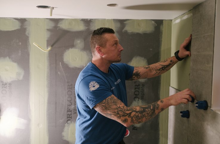 En mur- og flislegger arbeider med store fliser