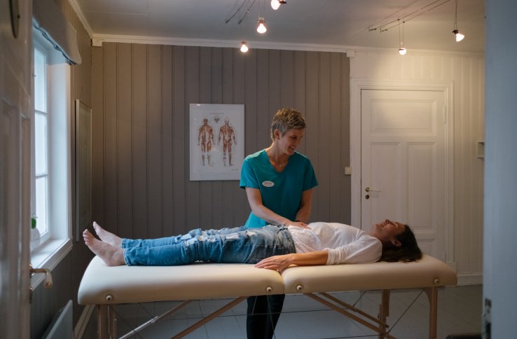 En dame ligger på en massasjebenk og blir behandlet av en soneterapeut