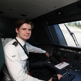 Ung mann i uniform i førerrommet på et lokomotiv.