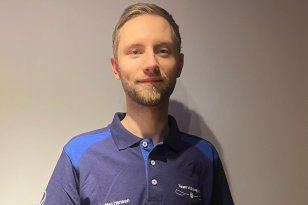 En mann i blå t-skjorte ser rett i kameraet.