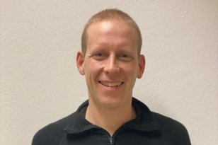 Portrett av mann i svart genser som smiler