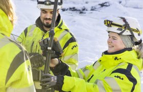 Bilde av landmålere i arbeidsuniform som betjener et landmålingsapparat