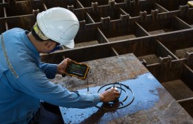 En NDT kontrollør tester en stålplate med hjelp av et apparat