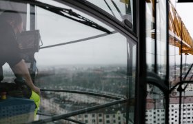 En kranfører sitter i bua og ser mot kranen som han styrer