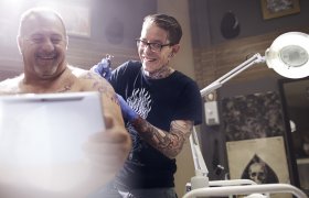 En tatovør tatoverer skulderen til en eldre mann
