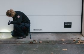 En skadedyrbekjemer ser under en garasjeport med lommelyktq