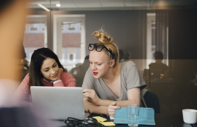 To mennesker på et kontor, diskuterer en tekst på en datamaskin