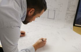 Byggingeniør sjekkar arkitekttegninger.