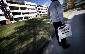 Eiendomsmegler bærer på et visningsskilt foran noen boligblokker