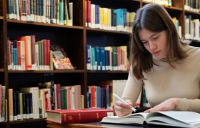 Filolog studerer en bok på et bibliotek