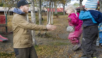 En mann holder armene ut for at en unge skal hoppe i armene hans.