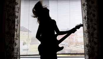 Ung gutt spiller gitar på gutterommet sitt. 
