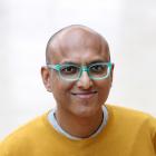 Profilbilde av Roshan das Nair, smilende mann med turkise briller og gul genser.