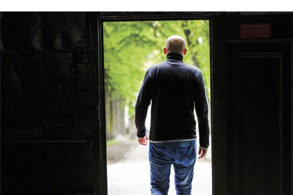 Bildet av forsiden på rapport om karriereveiledning i kriminalomsorgen. Mann som står med ryggen til i en døråpning.