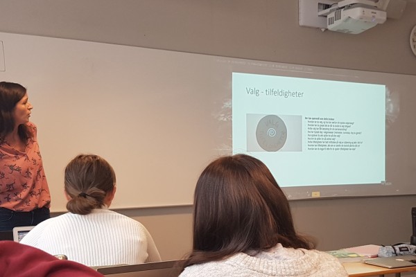 To elever og en lærer ser på storskjerm. 