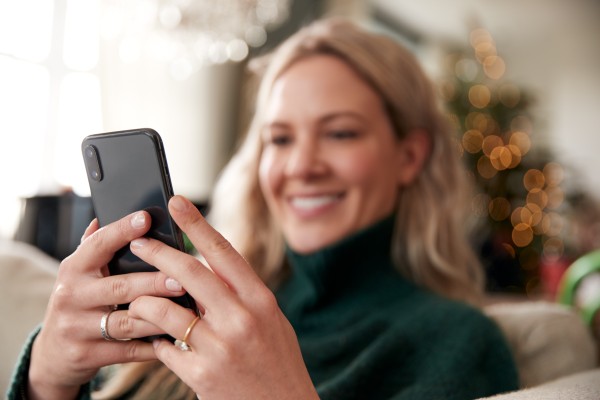 Blond dame som ser på mobiltelefonen og smiler