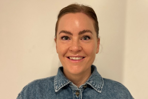 Bilde av smilende, mørkhåret ung dame i dongeriskjorte