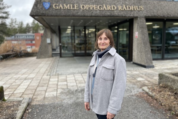 Foto av dame med grå byggnad i bakgrunnen