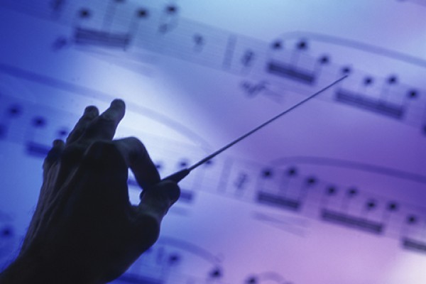 Silhouette of a hand conducting over sheet music